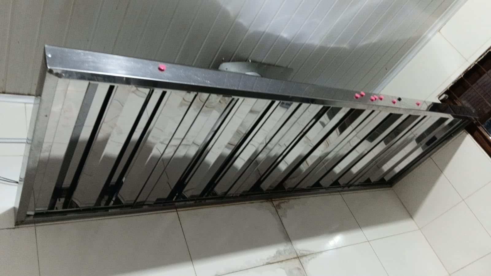 Coifa industrial em aço inox com filtros instalada em cozinha de restaurante